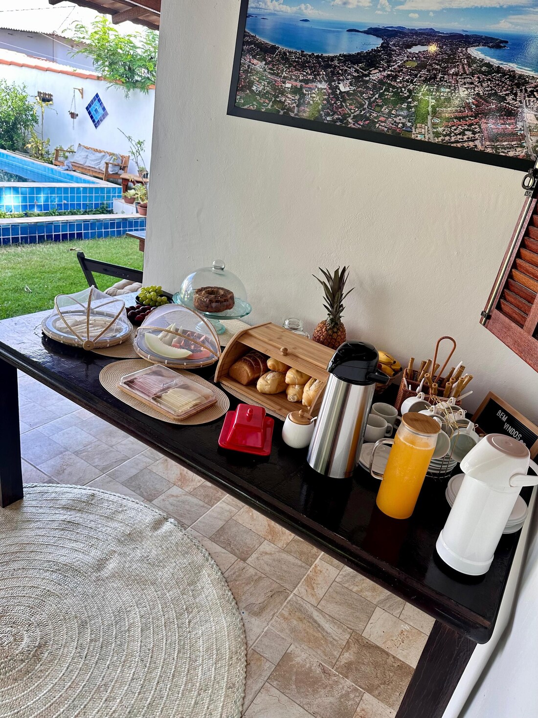 Mesa do café da manhã da Grão de Areia com frutas, pães, frios, bolo e bebidas