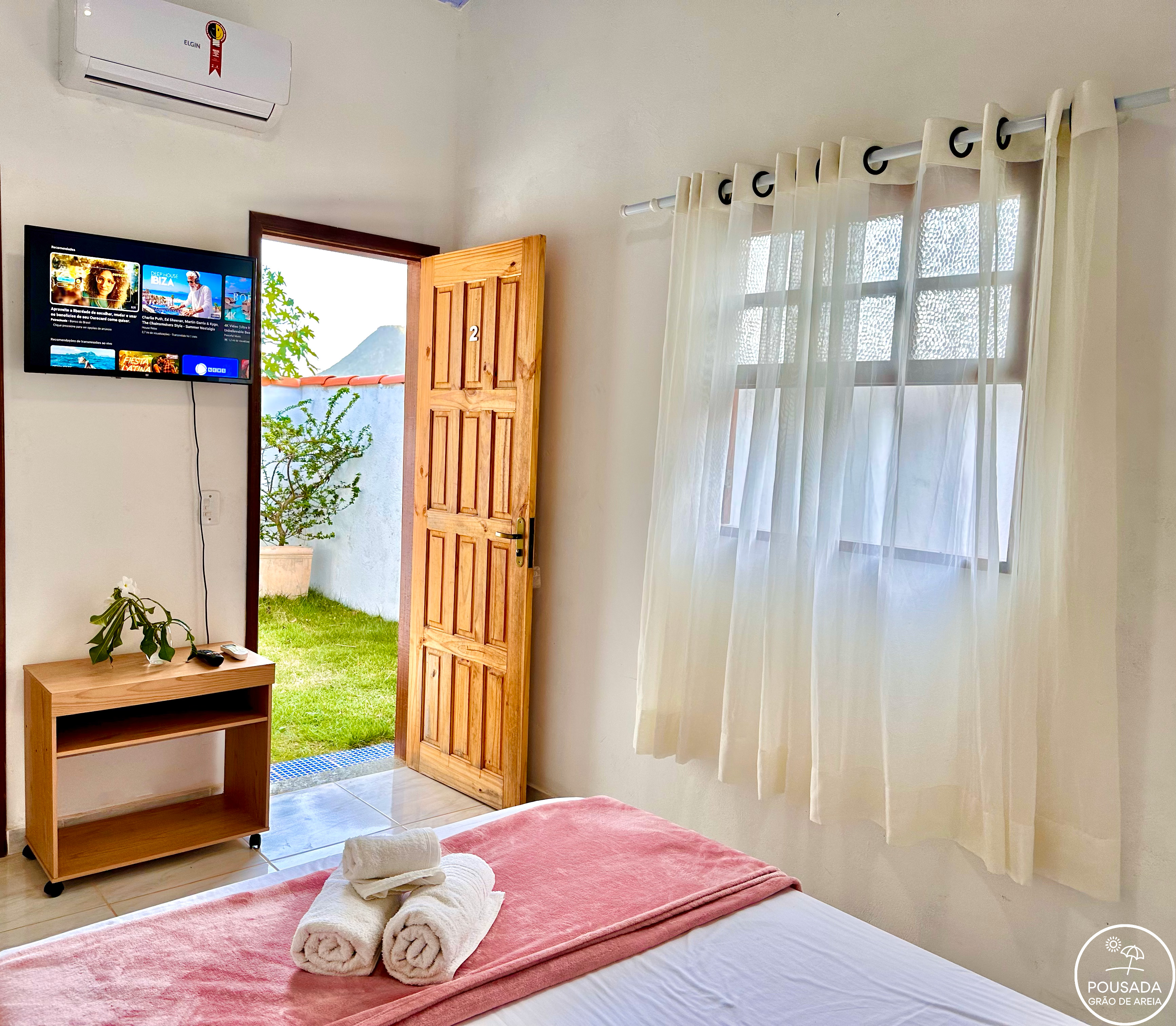 Suíte de casal com televisão, ar-condicionado e porta para o jardim